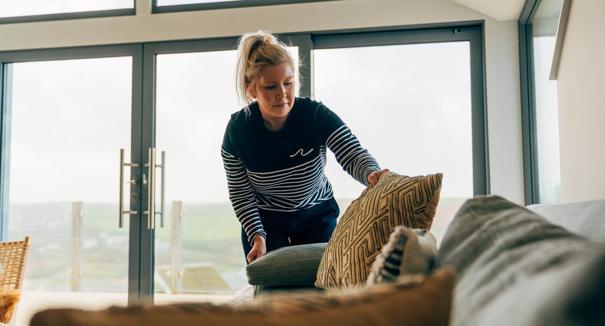 Team member arranging cushions in a beach retreats property